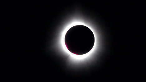 zoom-in of solar eclipse with deep red baily's beads visible on edge of the sun-moon limb