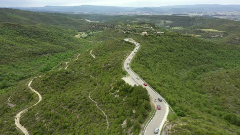 Aerial-view-following-convoy-classic-cars-driving-long-winding-forest-road-tour