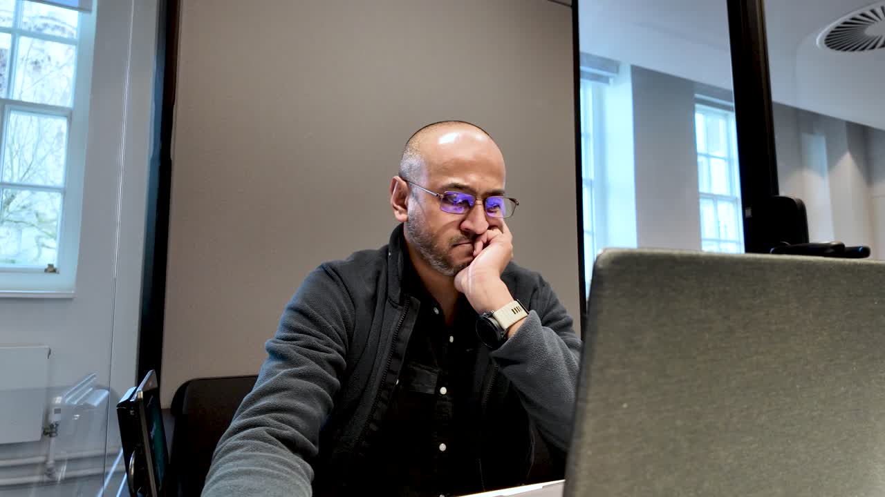 Focused employee working on a laptop inside a soundproof office pod, enhancing productivity and concentration in a modern workspace