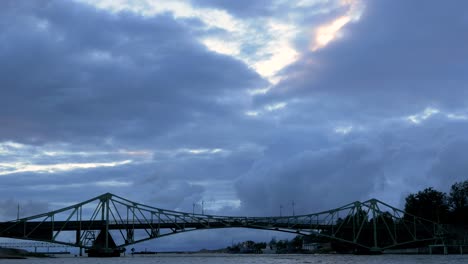 Beautiful-fast-moving-dark-gray-rain-clouds-over-the-Oskara-Kalpaka-swing-bridge-in-Liepaja-city-in-evening,-wide-shot