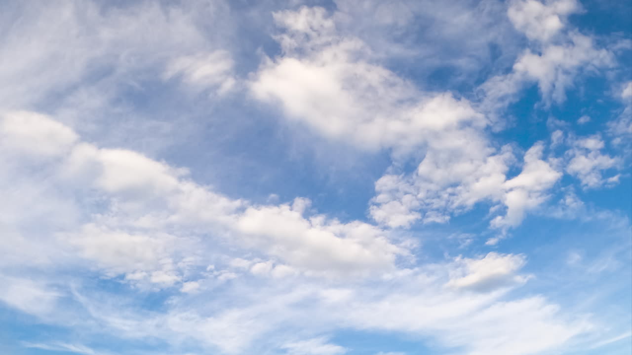 Light white cloudscape in the beautiful blue sky. Soft clouds floating in the atmosphere. Low angle view. Timelapse.