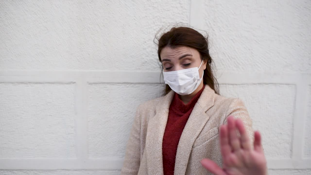 Bella ragazza con mascherina protettiva e vestiti alla moda tiene la mano alzata come segnale di stop - Concetto di nuovo stile di vita normale