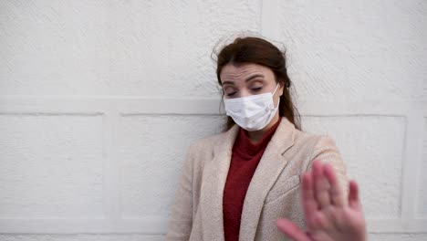 beautiful girl wearing protective medical mask and fashionable clothes holds hand up as stop sign new normal lifestyle concept