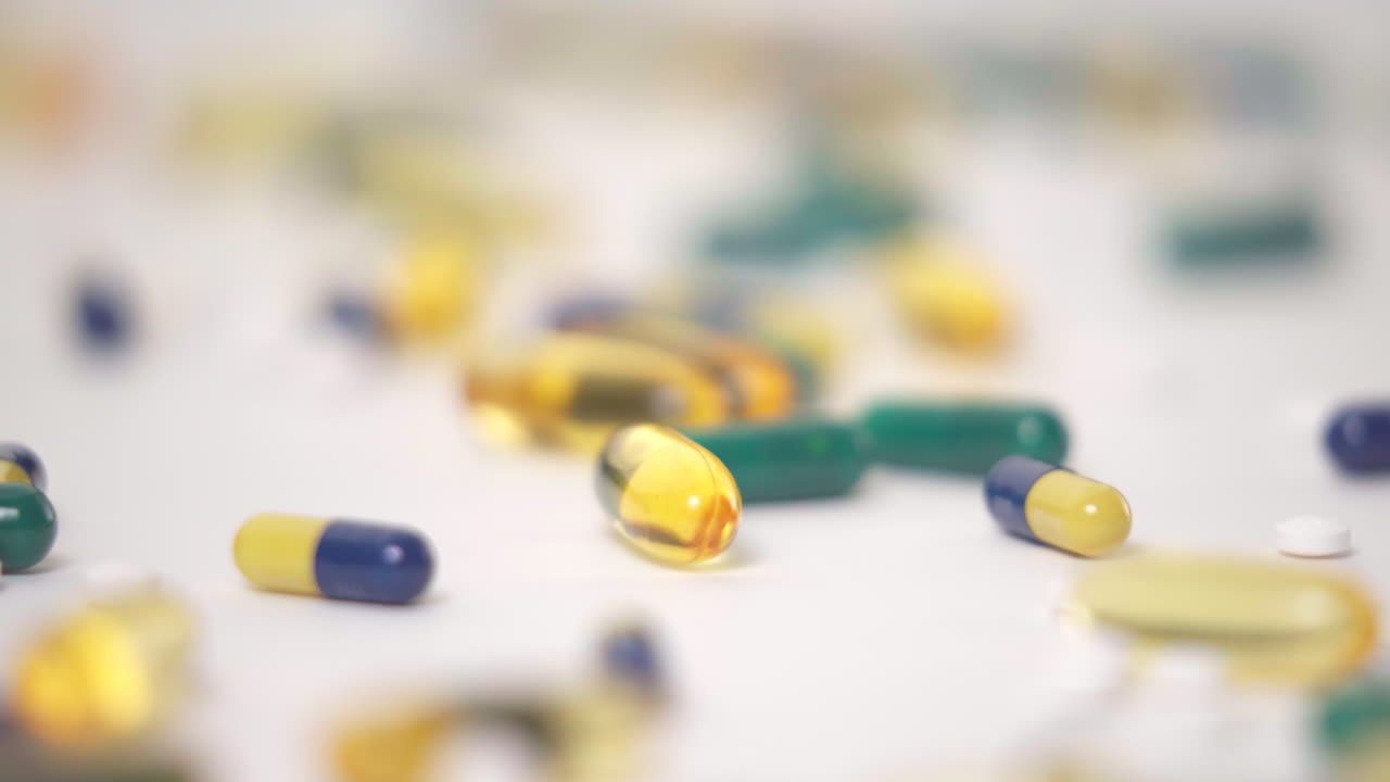 dolly macro delante de variedades de píldoras esparcidas sobre fondo blanco.