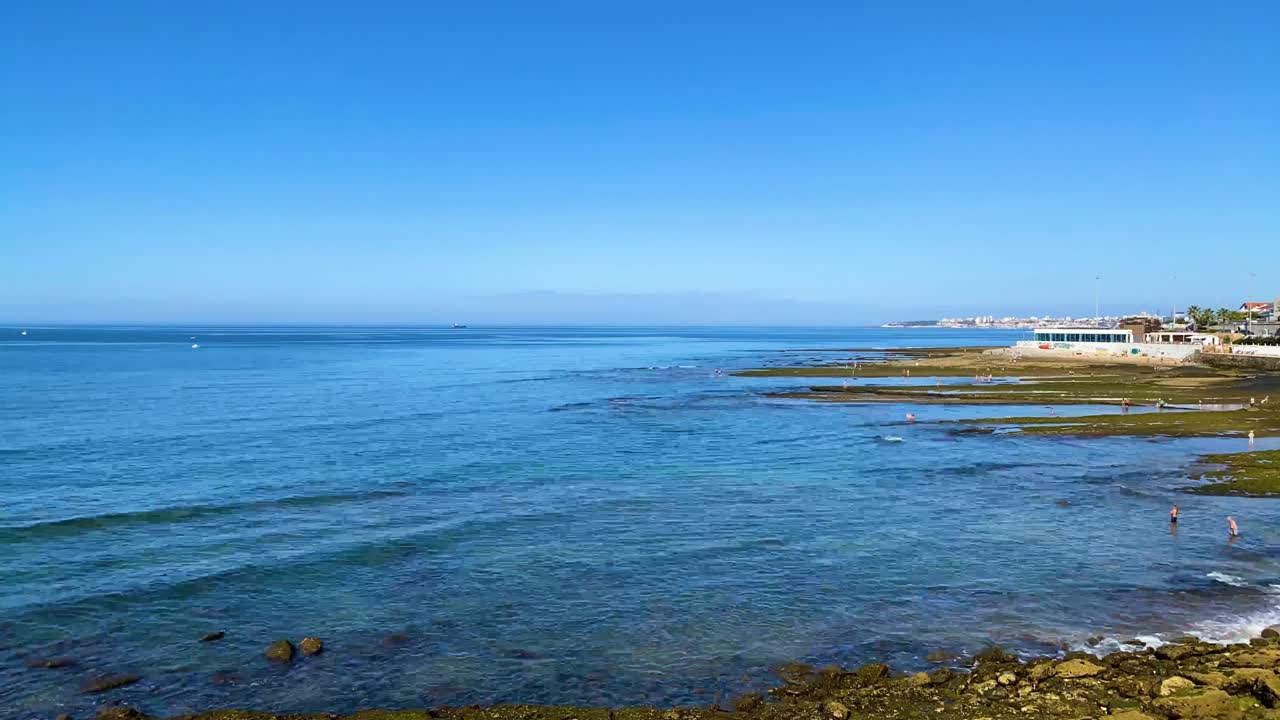 파레데 리스본 포르투갈의 해안 해변에서 일출 때 바다를 즐기는 일부 사람들을 드러내는 드론 샷