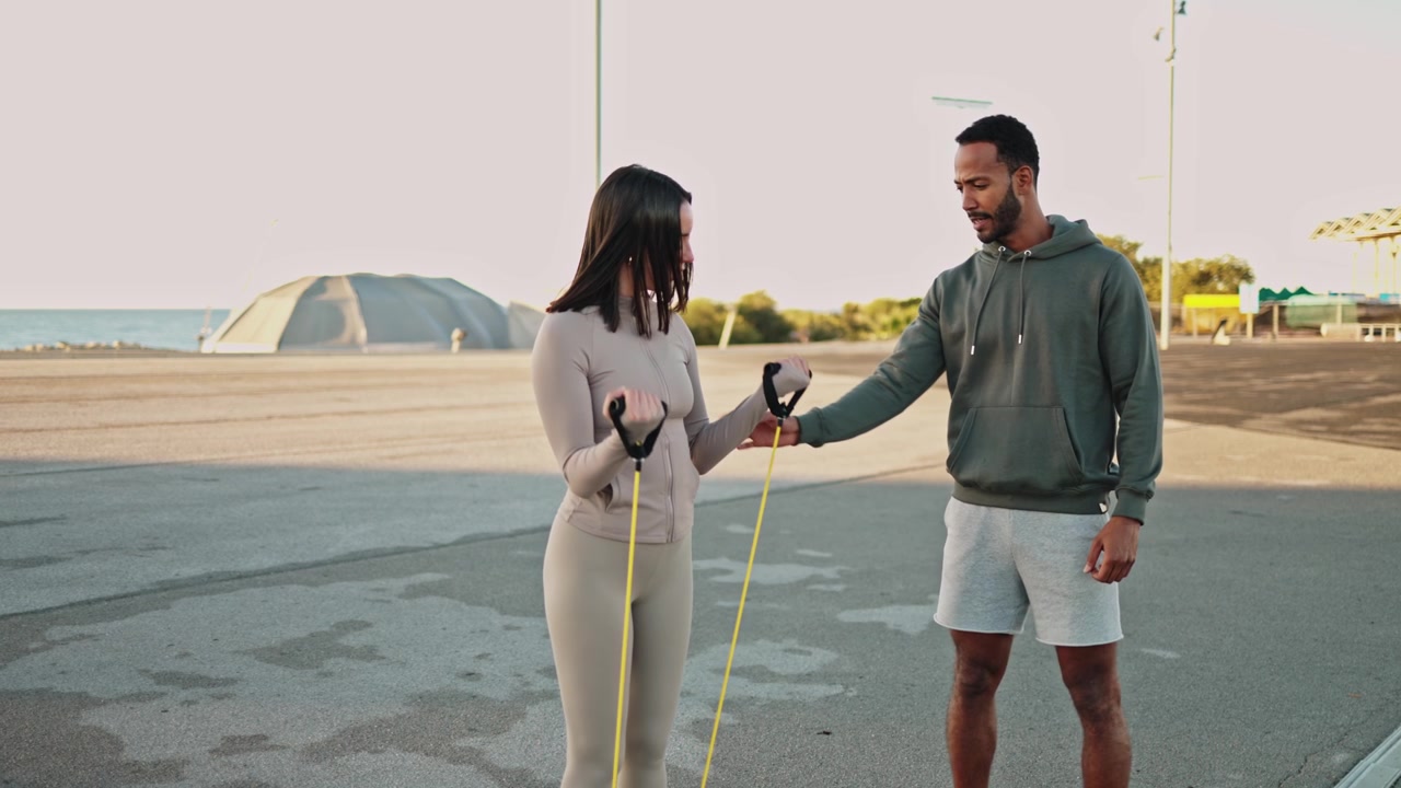 Personal Trainer che istruisce una donna con una fascia di resistenza all'aperto