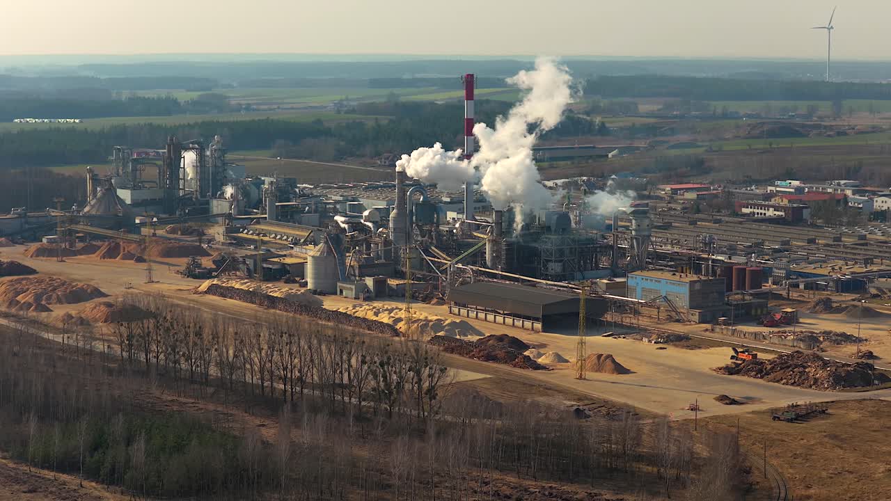 Establishing aerial shot of a large furniture production facility in grajewo, poland, with smoke billowing from its chimneys
