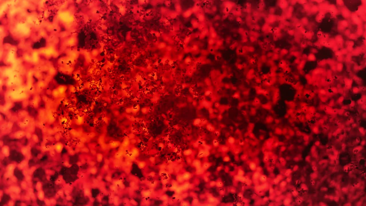 cristales de color naranja oscuro - azul timol, solo parcialmente solubles en agua - que se mueven sobre la superficie del líquido, detalle de la microscopía de primer plano, antecedentes científicos abstractos