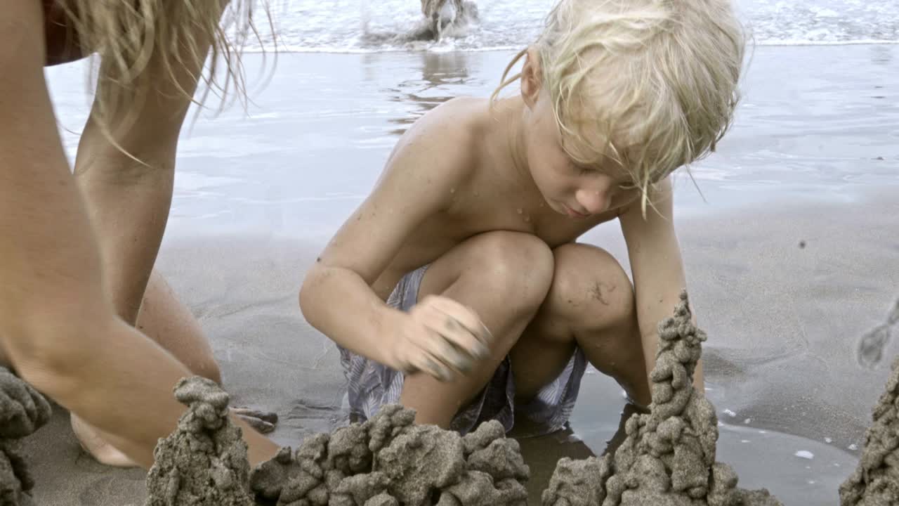 사랑스러운 아이가 엄마와 함께 모래 성을 짓고 있습니다.