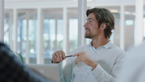 attractive-young-businessman-chatting-to-colleagues-in-boradroom-meeting-smiling-enjoying-casual-conversation-sharing-ideas-in-office-4k