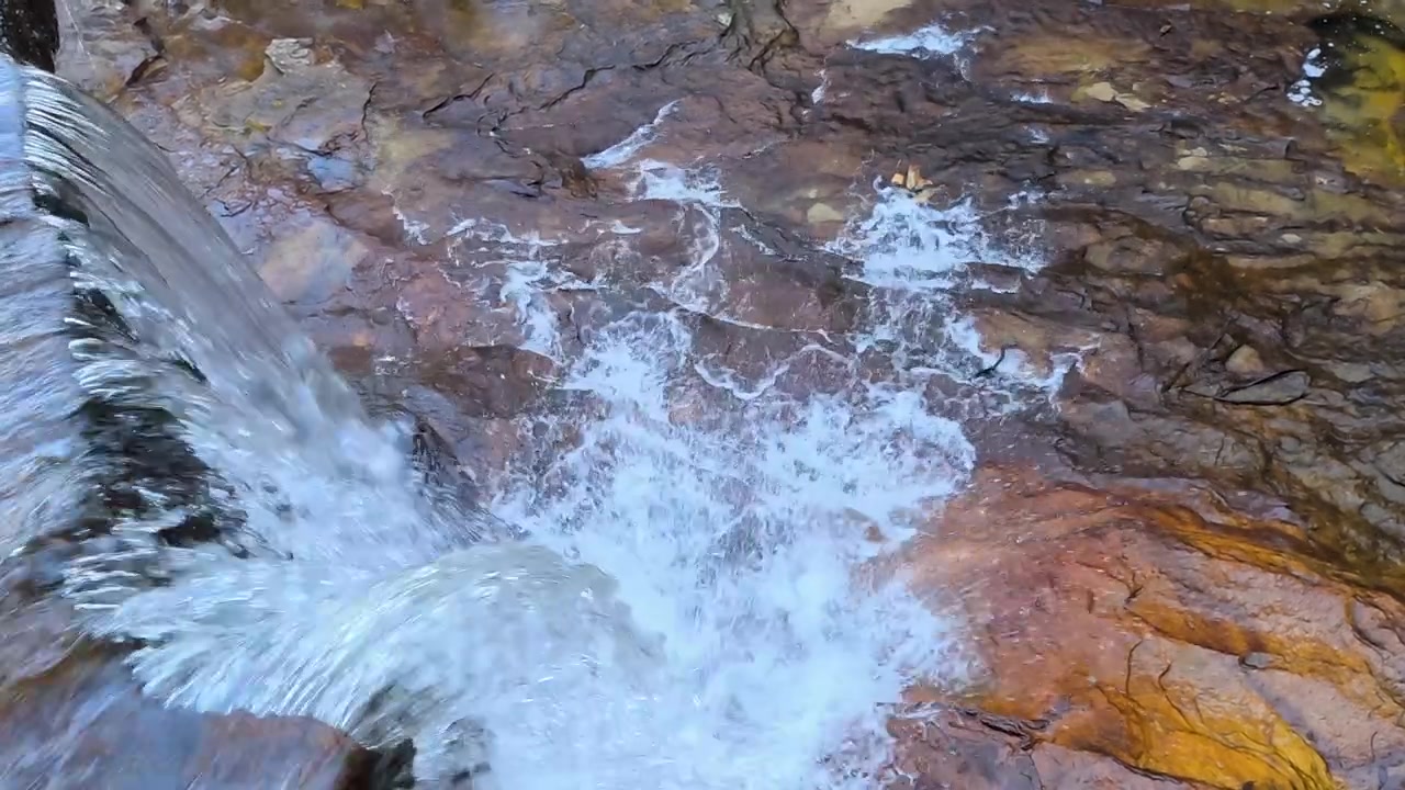 Ripresa dall'alto di acqua che scorre su un bordo di scogliera rocciosa nelle Blue Mountains, Australia