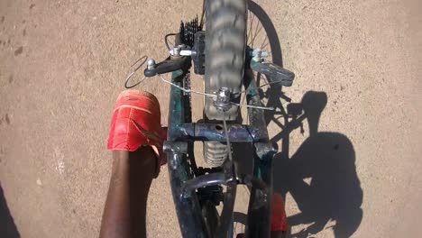 Top-view-of-Ethiopian-cyclist-legs-puddling-bicycle-wide-angle-red-shoes-mid-day