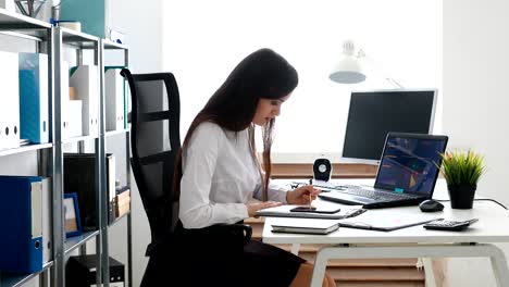 mujer de negocios hablando en teléfono inteligente y trabajando en una oficina moderna