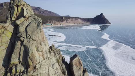 aerial view of drone flying near the shore rocks and frozen baikal lake in russia