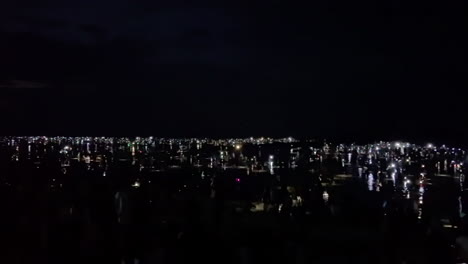 multitud en la oscuridad de la costa por la noche iluminada por linternas en el festival de bau nyale, lombok, indonesia