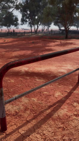 a red dirt outback scene with a metal fence and trees