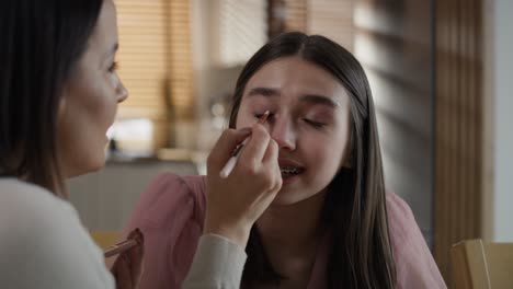 caucasian woman doing make up for her daughter