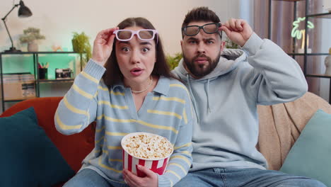 family man woman on couch eating popcorn, watching interesting tv serial, sport game online at home