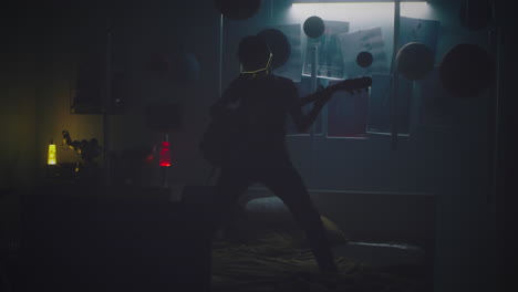 teenager playing guitar in a neon lit bedroom