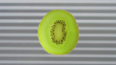 un pedazo de fruta de kiwi cae y salpica