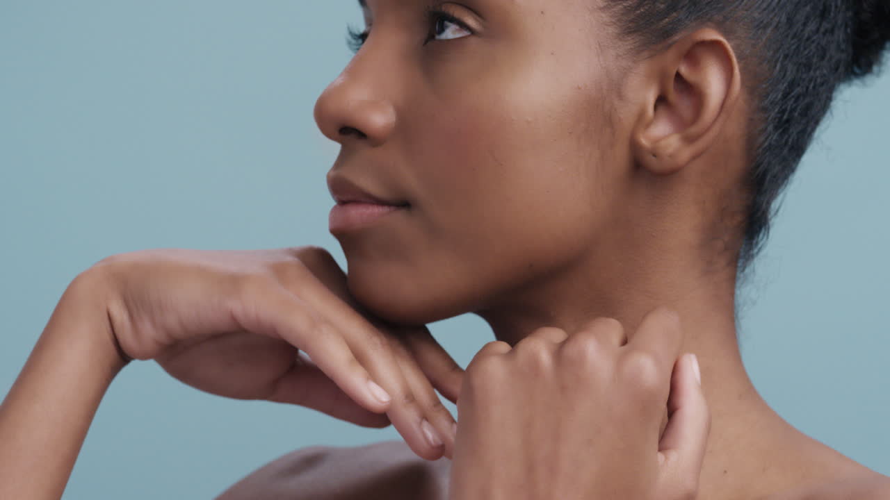 ritratto di bellezza ravvicinato donna afroamericana attraente che tocca le piume del viso che cadono sulla pelle morbida cura naturale della pelle che accarezza delicatamente la pelle sana al rallentatore