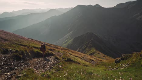 Tourist-backpacker-descending-to-the-valley-during-sunrise,-High-Tatras