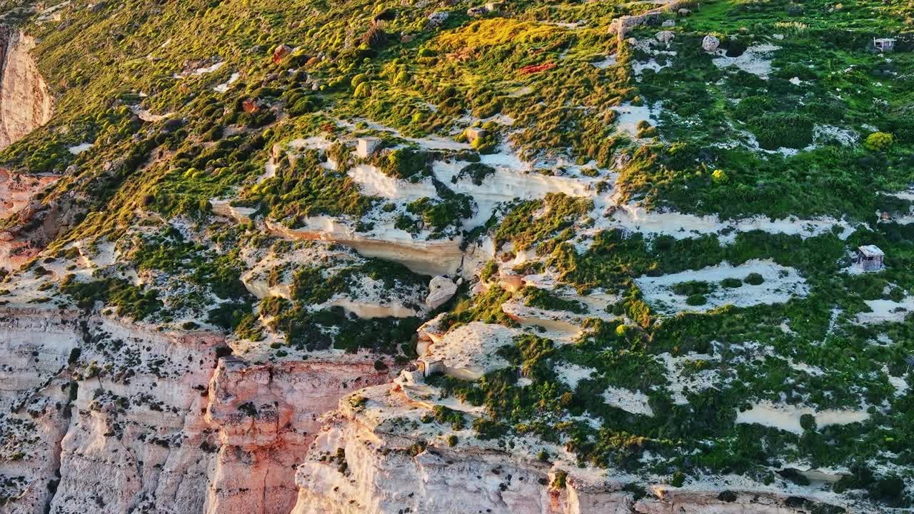 Aydınlık bir günde Malta'da yeşil kayalıklar, masmavi denize bakıyor.