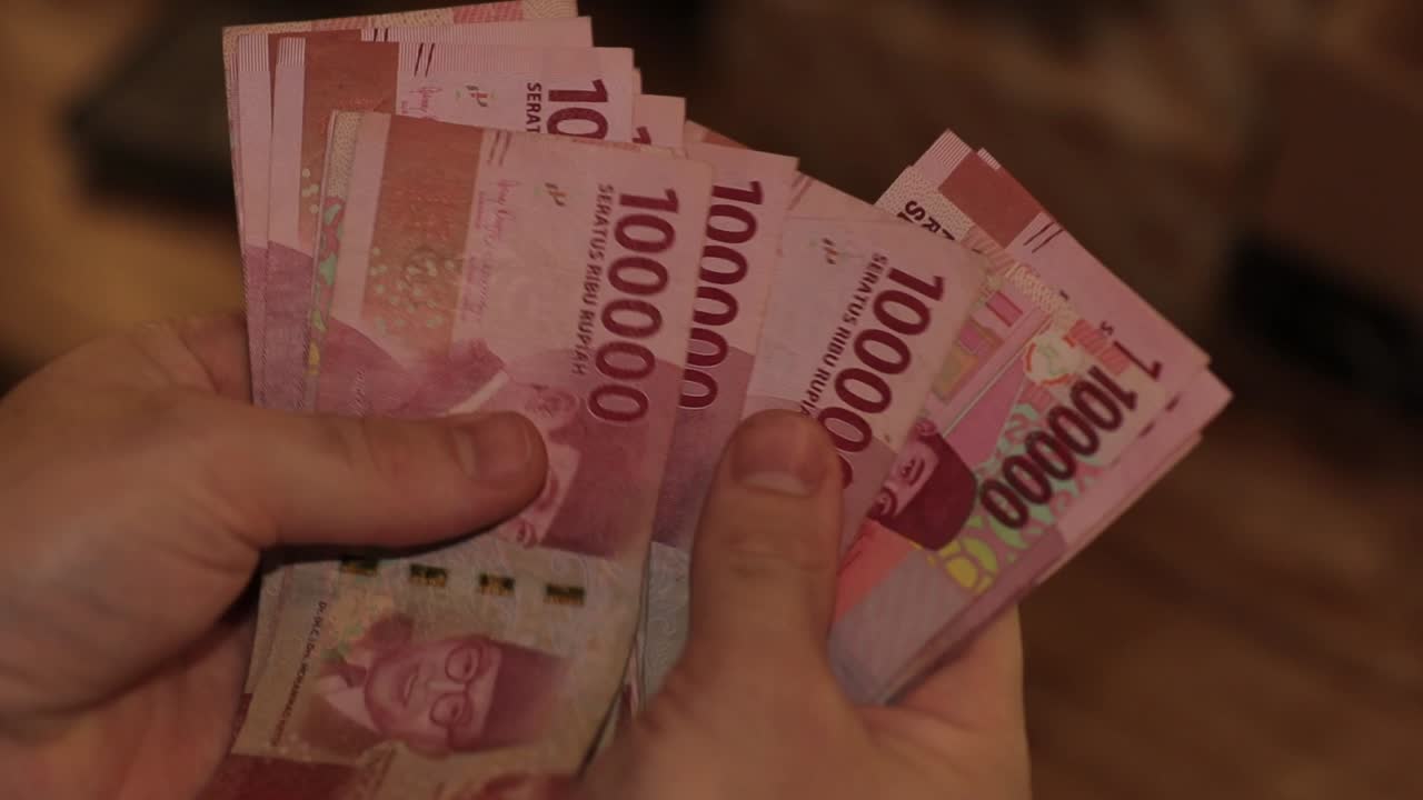 Nahaufnahme: Hand zählt ausgebreitete indonesische Rupiah-Banknoten.