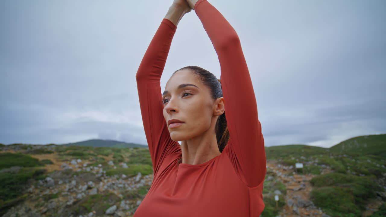 mujer serena practicando yoga en colinas rocosas logrando paz y equilibrio de cerca.