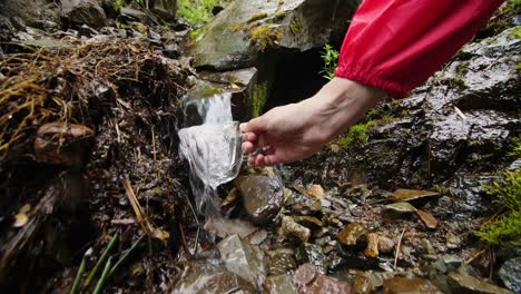 person drinking water from a mountain stream