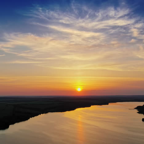 amazing orange sunset over the river. magic aerial view of evening sun among clouds. golden path of setting sun on the calm river in nature. slow motion camera.