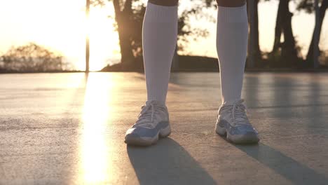 Footage-From-Down-And-Up-Below-A-Full-Length-Of-A-Young-Female-Basketball-Player-In-Hoodie-And-Shorts-Standing-On-A-Local-Basketball-Court-With-Ball-In-Her-Hand