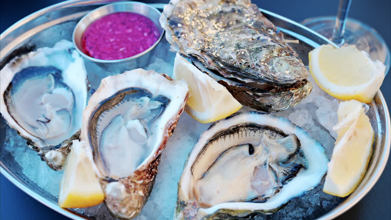 Close up of a bucket with raw oyster with lemons on ice at a restaurant