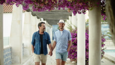 front view of happy guys walking in park with beautiful trees