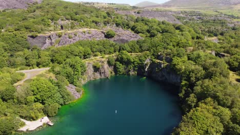 Vista-Aérea-De-La-Cantera-Minera-De-Pizarra-De-Dorothea-En-El-Valle-Montañoso-De-Snowdonia-Con-Un-Hermoso-Lago-Azul-Brillante