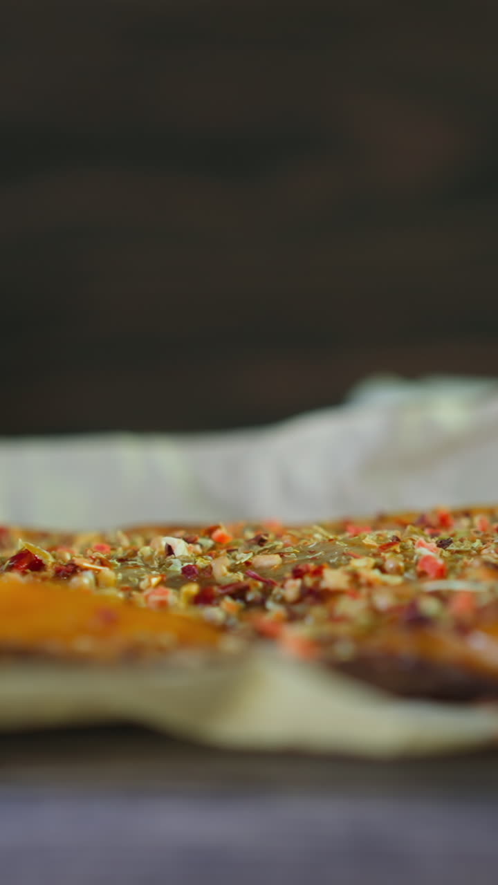 Piece of smoked trout fish with different spices lies on crumpled parchment paper served on board in restaurant close view slow motion