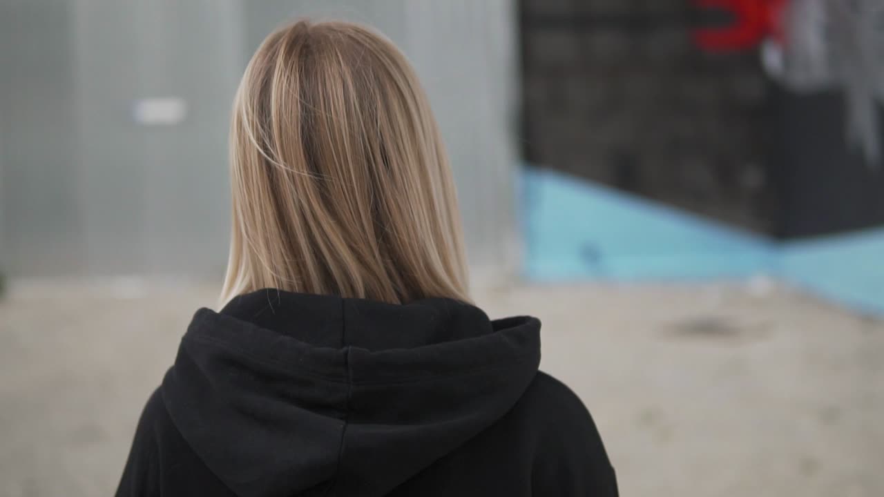 야외에서 얼굴 마스크를 쓰고 카메라를 바라보는 젊은 금발 여성의 슬로우 모션