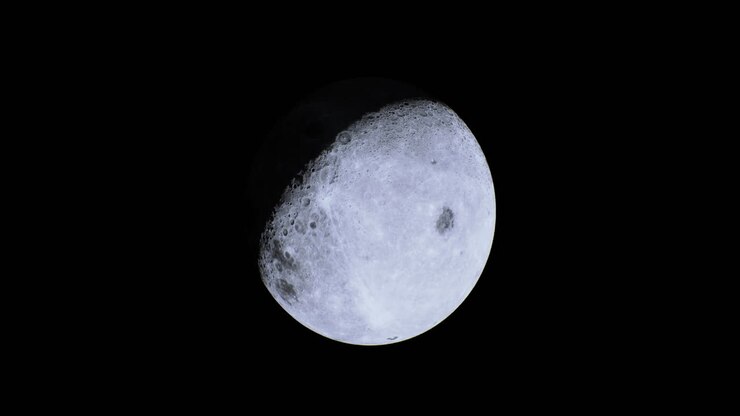 Lua iluminada no céu noturno mostrando sua superfície e características cheias de crateras