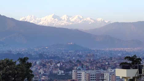 a day to night time-lapse over the city of kathmandu with the himalaya mountains in the background