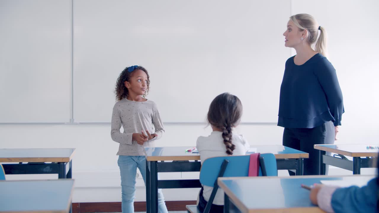 Friendly teacher helping mix raced pupil to answer the question in front of her friends