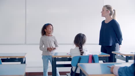 friendly teacher helping mix raced pupil to answer the question in front of her friends