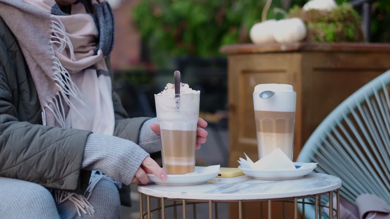 Woman enjoying lattes in an outdoor cafe during autumn