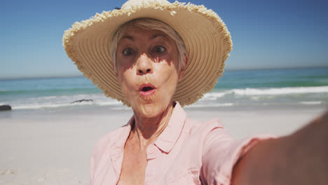 mujer caucásica mayor disfrutando del tiempo en la playa con el mar en el fondo