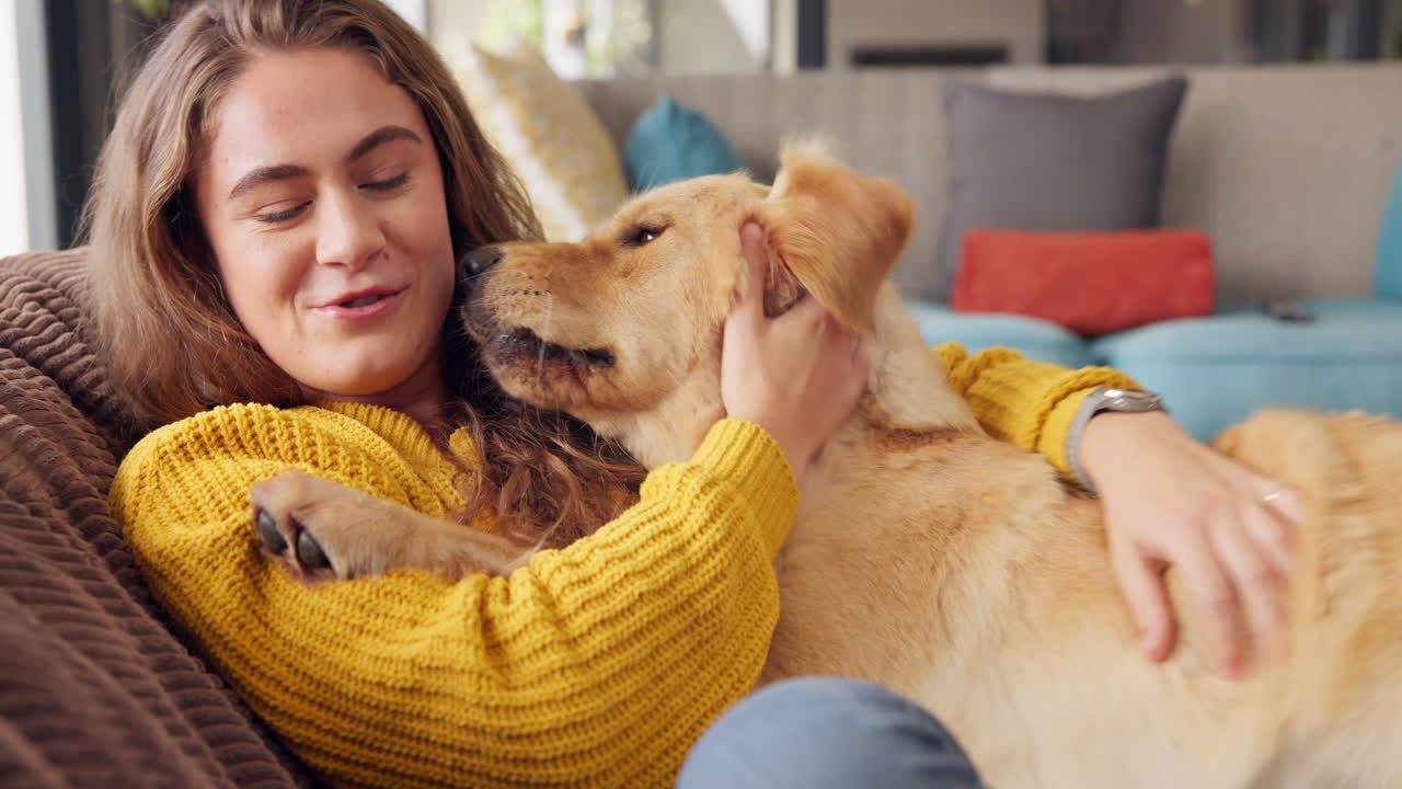 Woman cuddling with her golden retriever on the couch