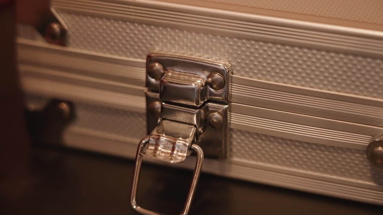 un hombre desbloquea la cerradura de un maletín pero no abre el caso