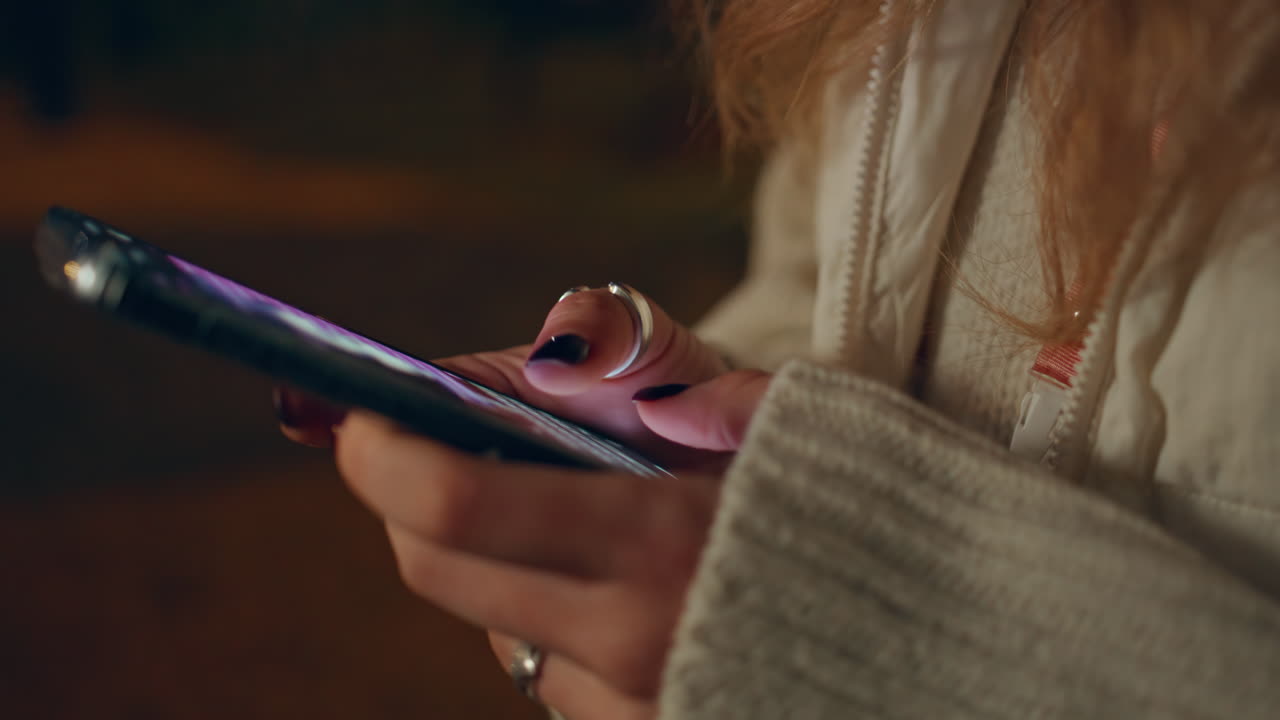 mano de primer plano escribiendo pantalla táctil de teléfono inteligente por la noche. mujer desconocida enviando mensajes de texto