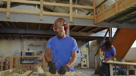 african american male team feeding planks into table saw hand-sawing pieces and inspecting boards