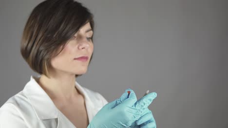 médico femenino preparando cuidadosamente y inyección aislada en fondo gris. enfoque en las manos. concepto de atención médica y medicina