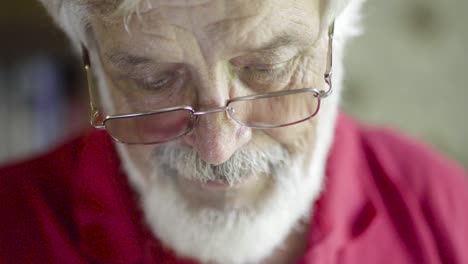 senior man in red t-shirt and eyeglasses talking on phone