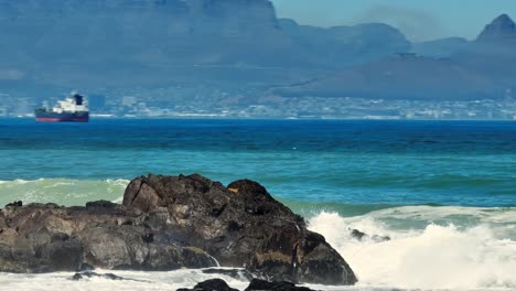 Tele-drone-shot-off-waves-hitting-the-rocks-in-front-of-Big-Bay,-Cape-Town